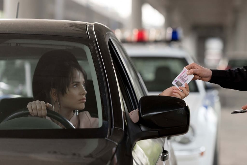 young-woman-in-car-giving-driver-license-to-police-2021-09-02-03-32-28-utc.jpg